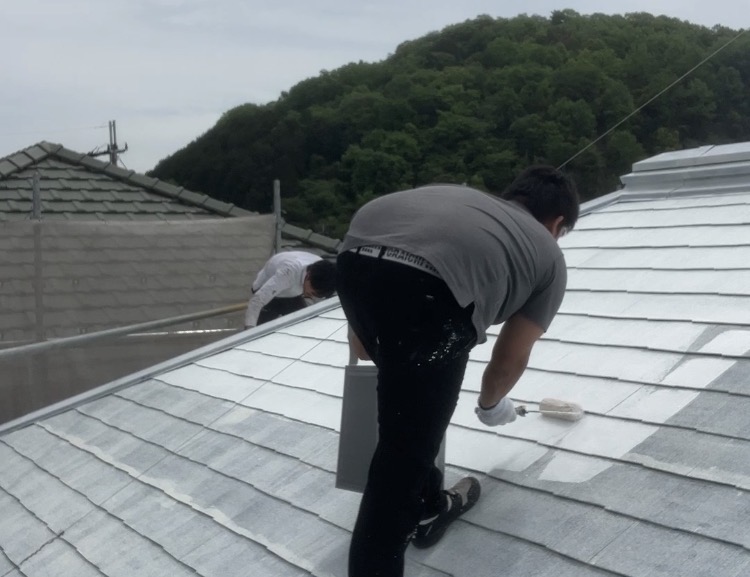 屋根塗装の下塗り2回目を行う藤原ペイント代表・藤原健太